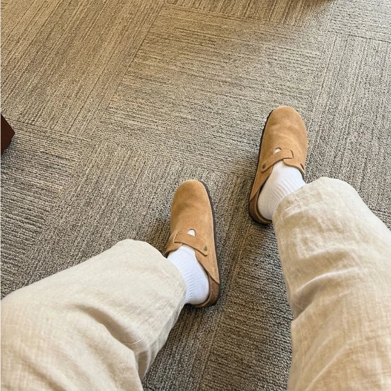 Mules couleur beige confortables portées au travail avec une tenue beige clair et une vue sur la moquette.