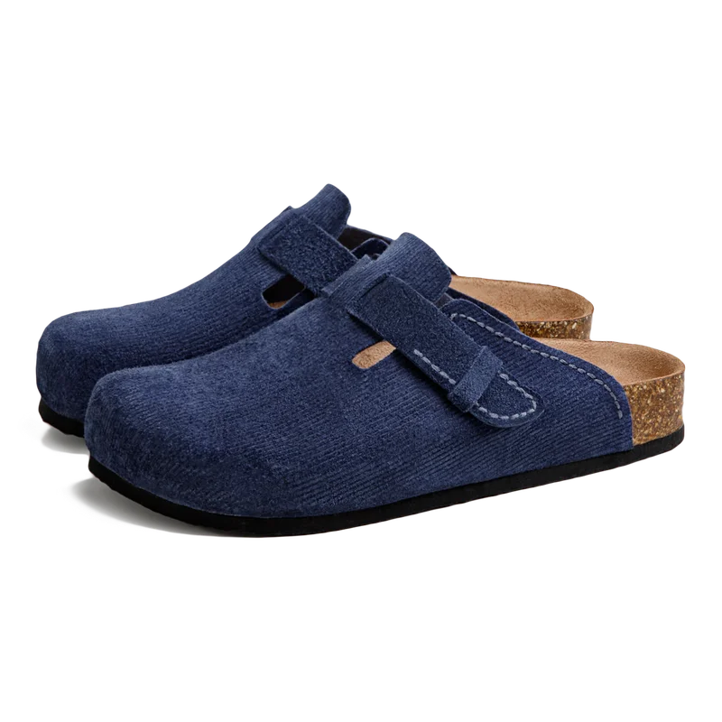 Mules en daim bleu marine vue trois-quarts avant avec boucle textile et semelle liège granulée sur fond blanc