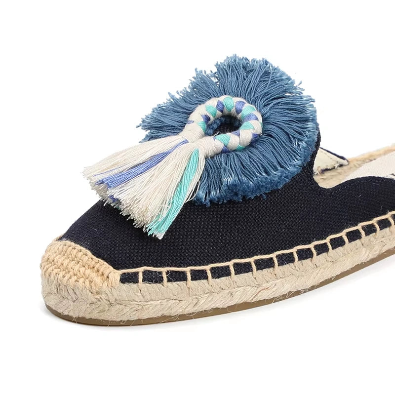 Détail de la mule espadrille bleu marine tressée avec pompon bleu et blanc sur l’avant.