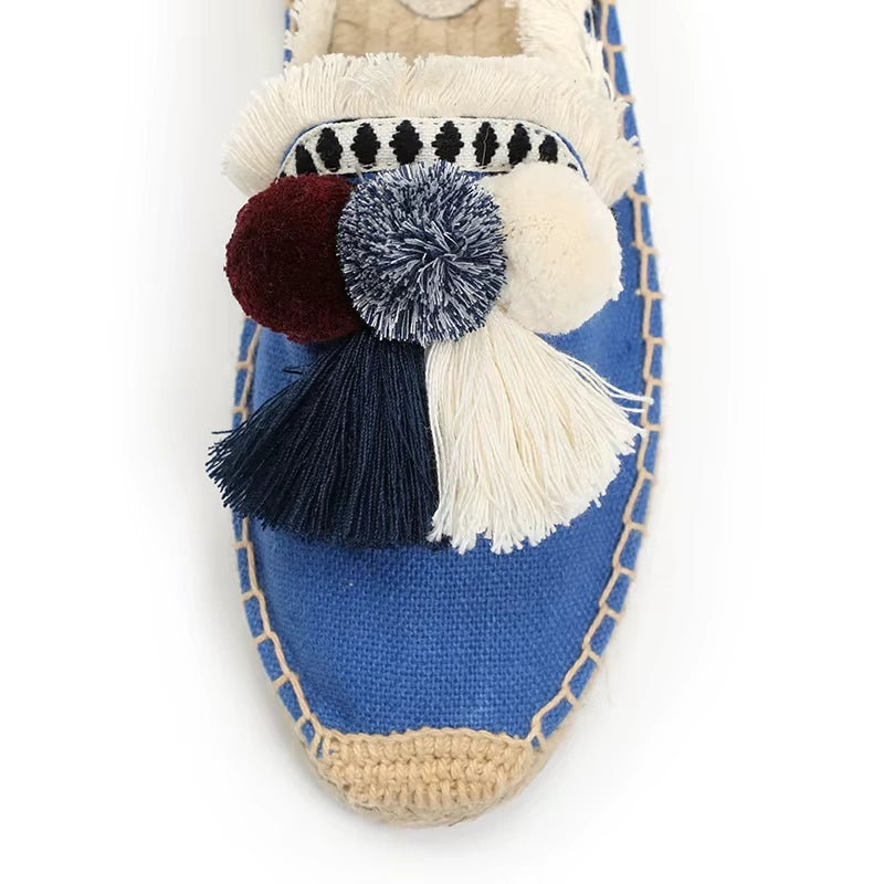 Détail des pompons décoratifs sur mules espadrilles bleues.