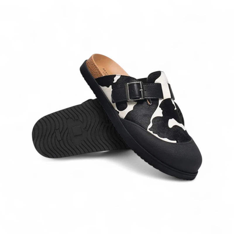Mules Vache Noir et Beige pour femme avec semelle noire antidérapante, photographiées en position croisée.